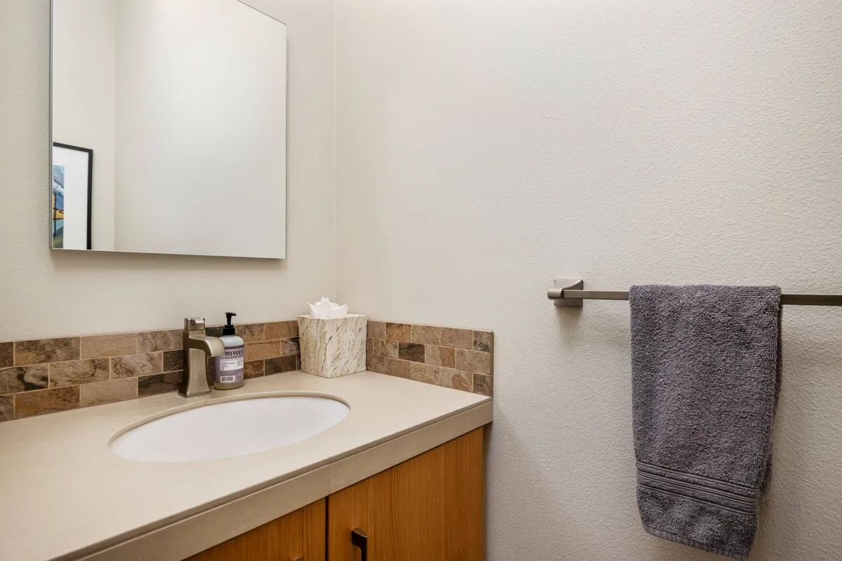 A spa-like bathroom with a sleek sink, elegant mirror, plush towel, and a decorative box, all bathed in soothing light. The mood is calm and serene, ideal for personal grooming and relaxation.