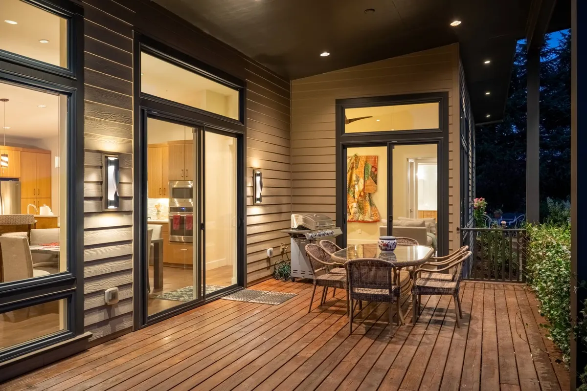 An elegant outdoor dining setup featuring a table, grill, and wall art, surrounded by lush greenery. The area invites relaxed gatherings and culinary experiences with a scenic backdrop.